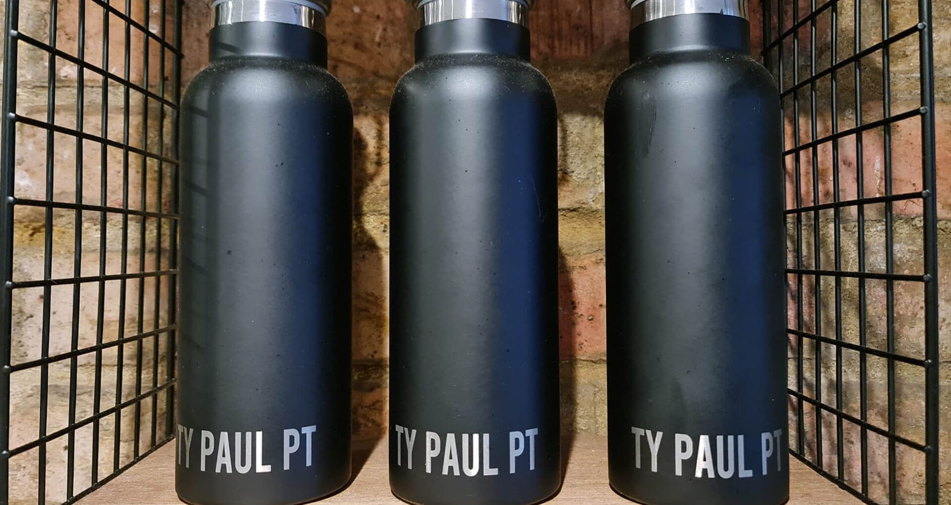 Three black bottles lined up with Ty Paul written on each bottle